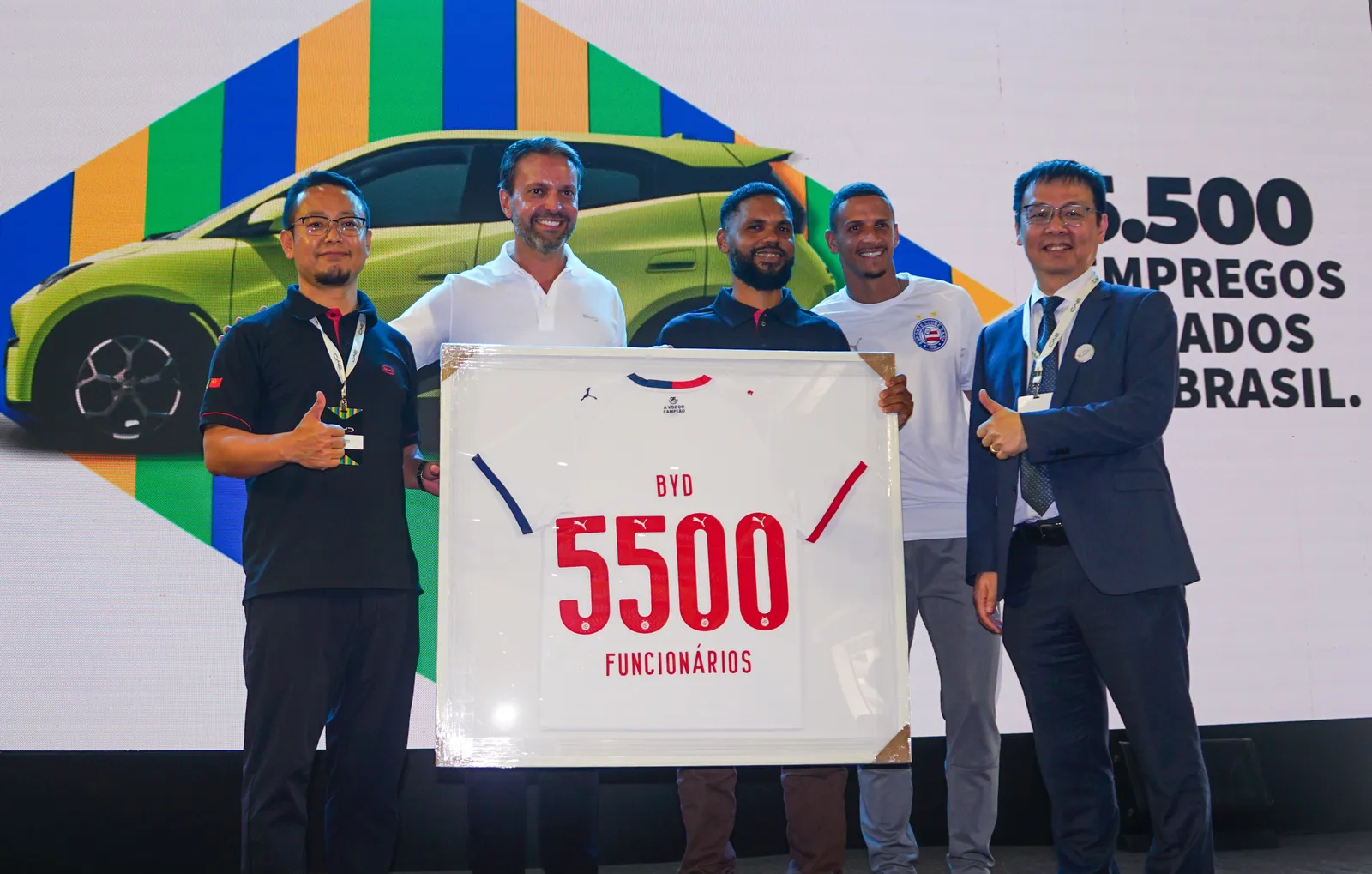 Executivos da BYD seguram camisa com a inscrição 5500 funcionários