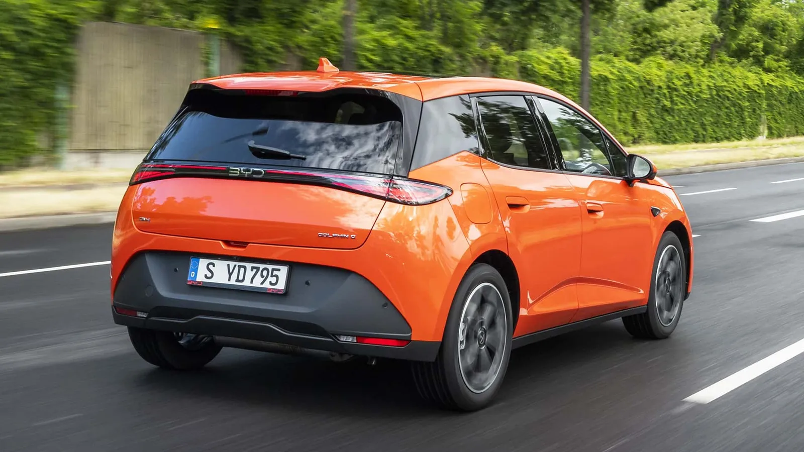 BYD Dolphin G laranja visto de trás, em movimento
