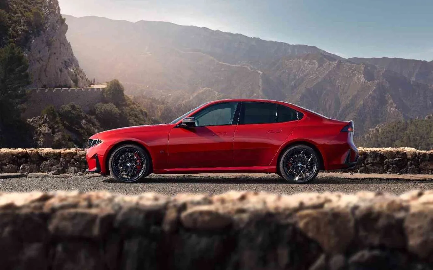 BMW M350 xDrive vermelho visto de lado, estacionado em uma estrada de montanha