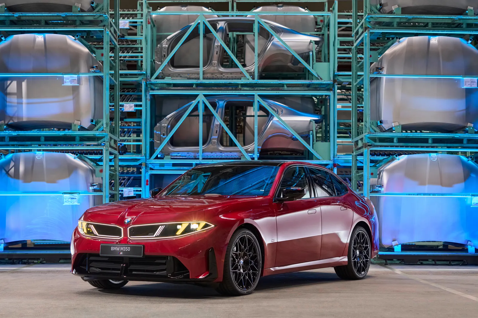 BMW M350 xDrive vermelho diante de estrutura com carrocerias na fábrica de Dingolfing