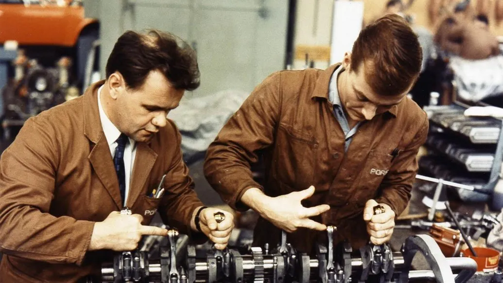 Dois mecânicos da Porsche montando um virabrequim de motor de corrida, em foto antiga