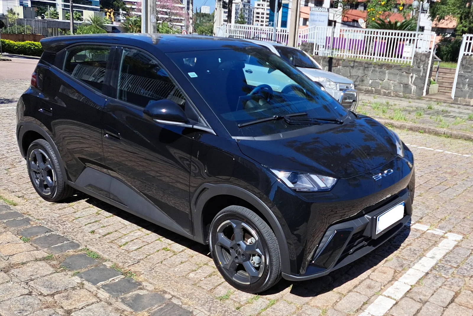 BYD Dolphin Mini preto estacionado em rua de paralelepípedos